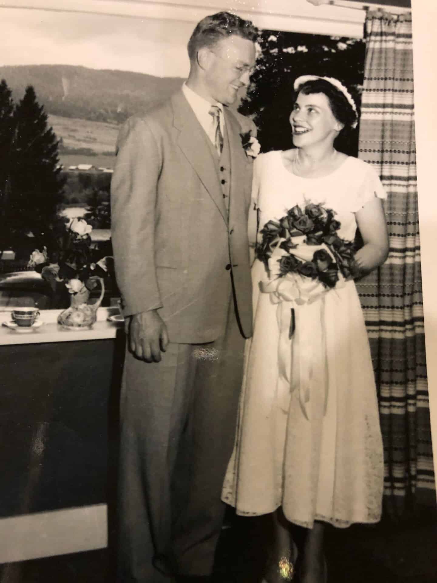 Black and white photo of Noel smiling at Joan holding a bouquet on their wedding day