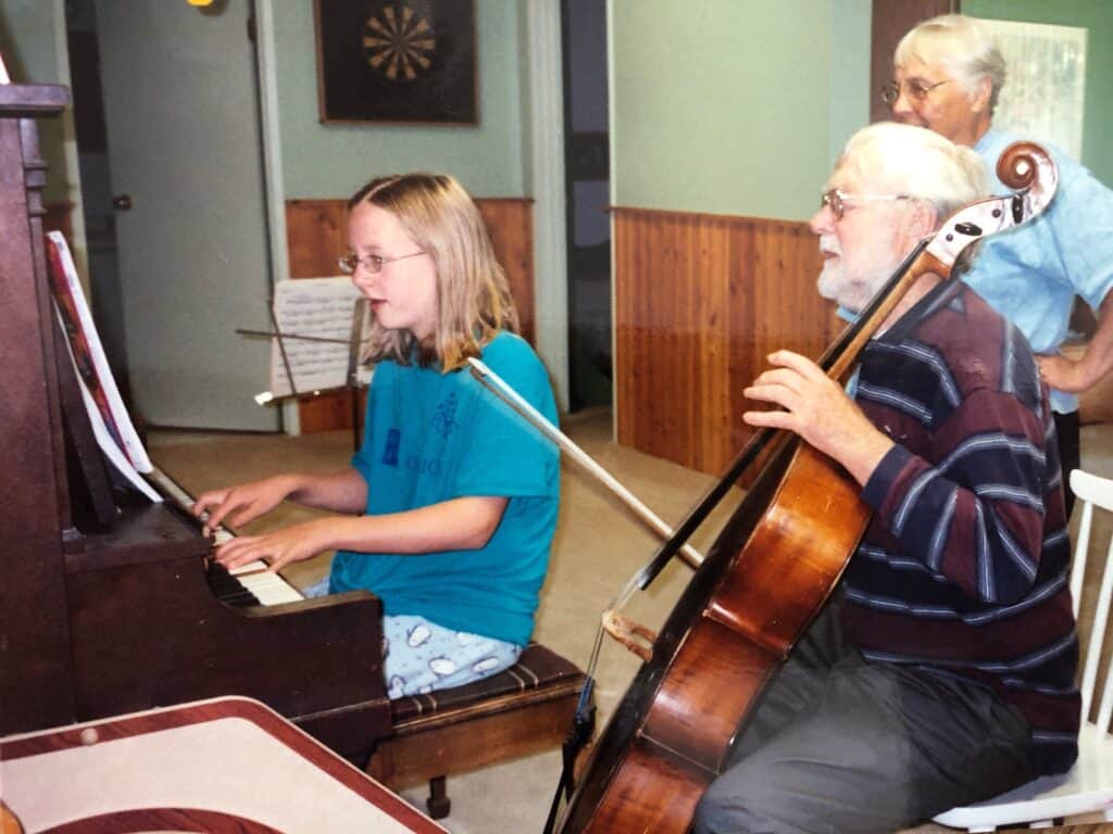 Young girl playing piano while Noel accompanies her on cello, in a music class
