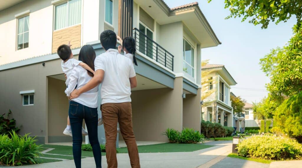 Family with two children standing outside and looking up at a modern home