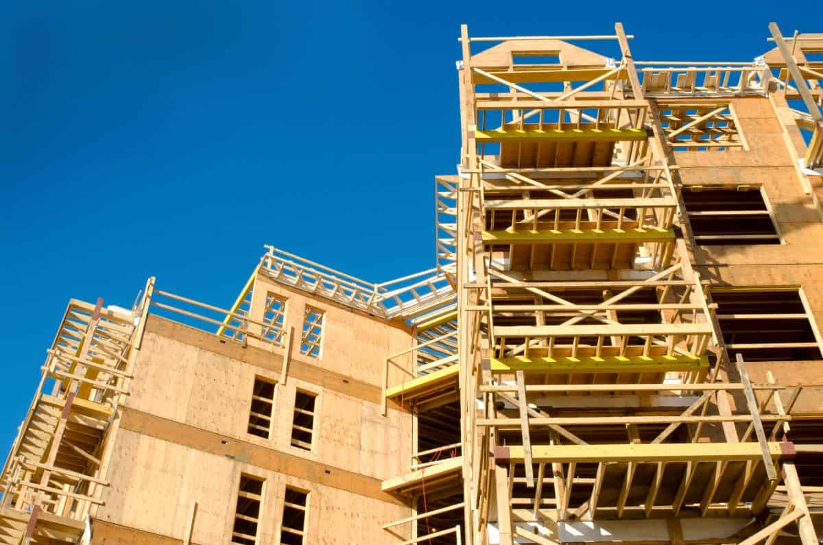 Wooden framing of a building under construction against a clear blue sky.